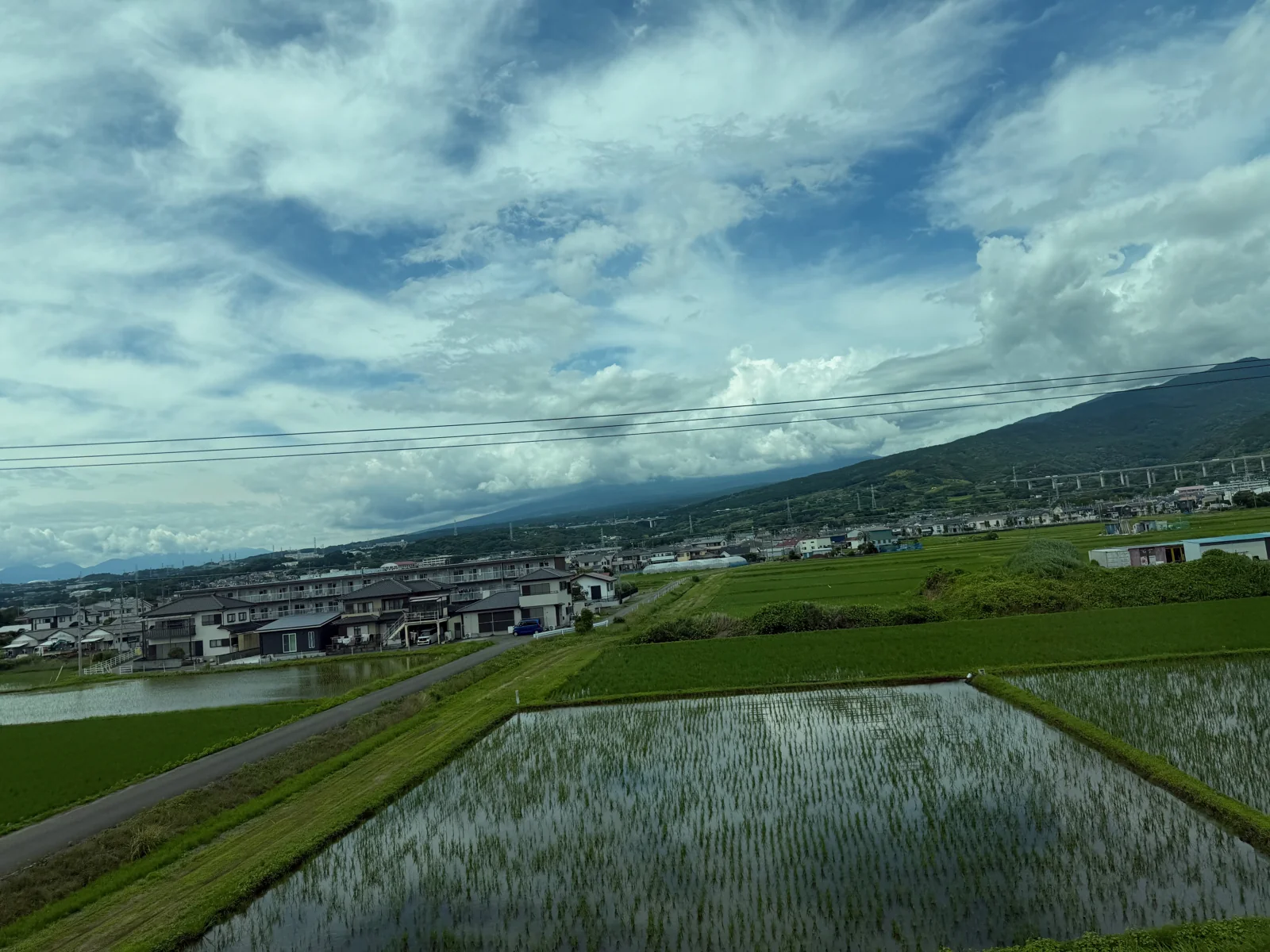 Fields and buildings seen through the train window near Fuji.