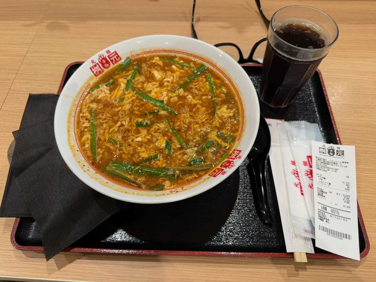 A large bowl of soup with egg and green vegetables, with a Coke at the Makuhari mall.