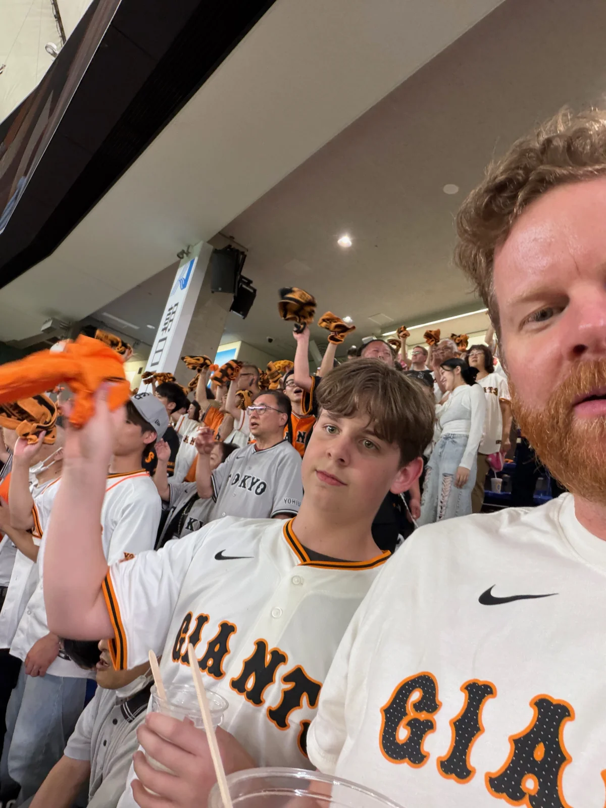 Oliver and Chris wearing Giants jerseys in the Tokyo Dome stands.