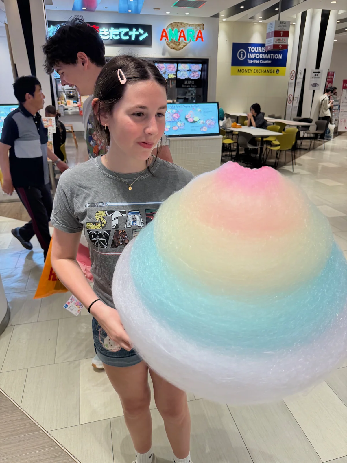 Ady holding an enormous rainbow cotton candy at DiverCity.