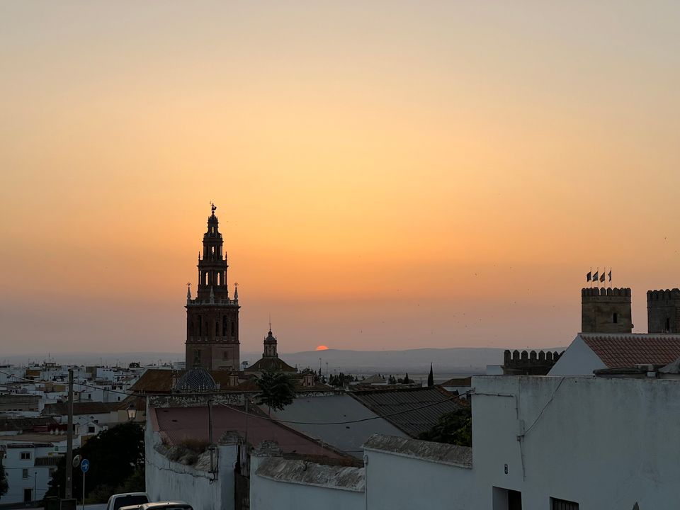 Sun setting behind a hill in Carmona, Spain. The city skyline is in the foreground.