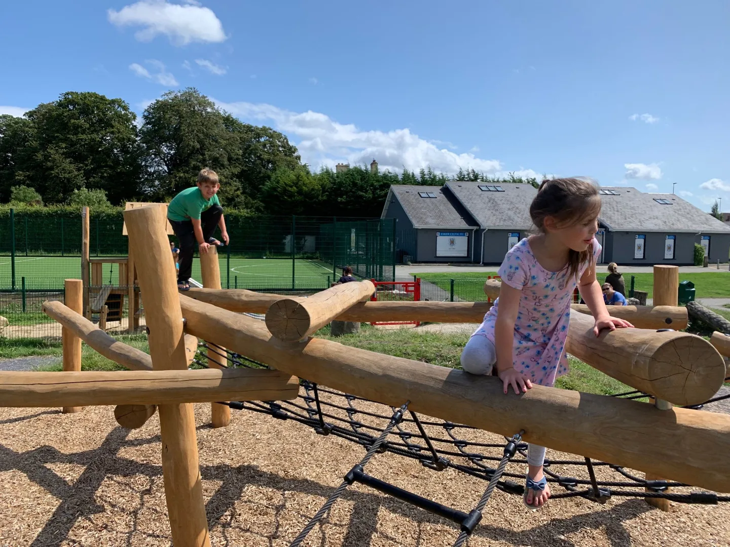 Children riding a wooden playground seesaw