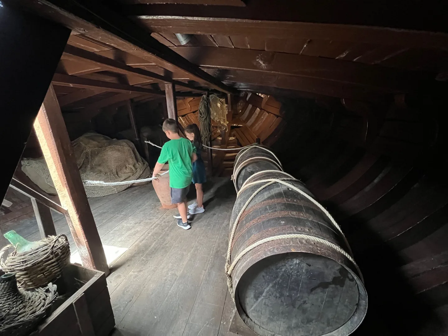 Child exploring barrels in a ship's hold