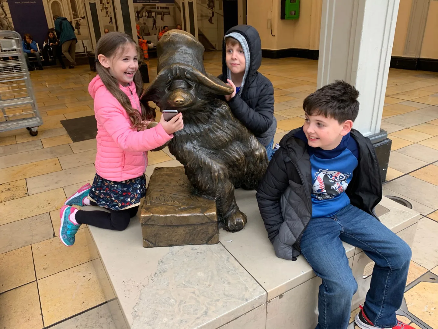 Children posing beside a bear statue