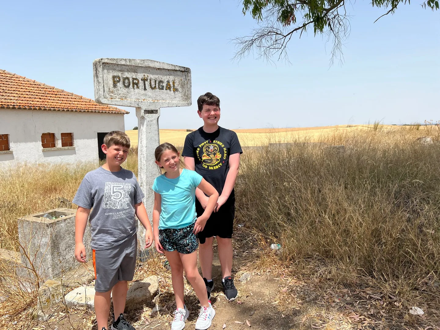 Children beside a Portugal border sign