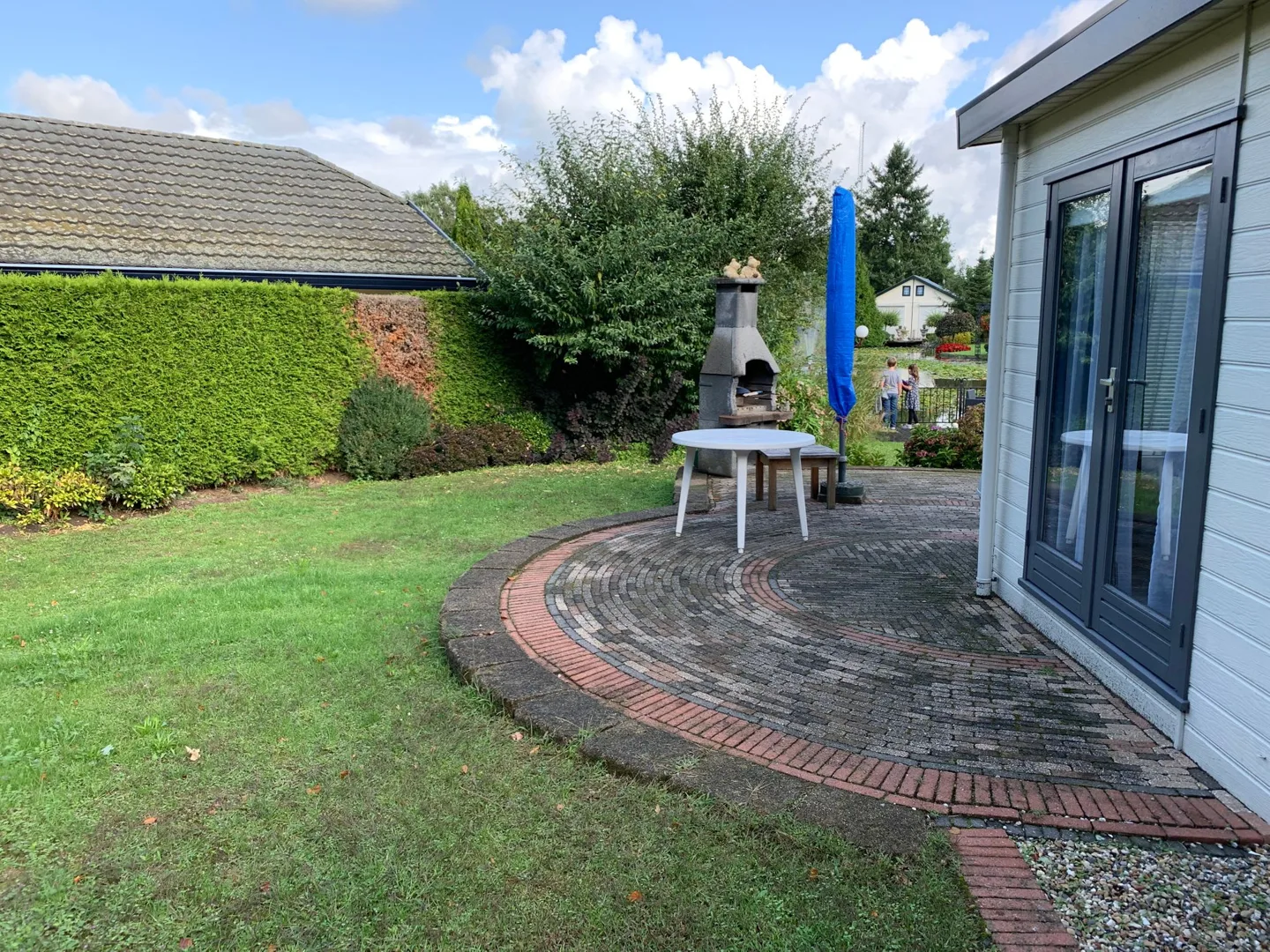 Sunny patio beside a small house and lawn