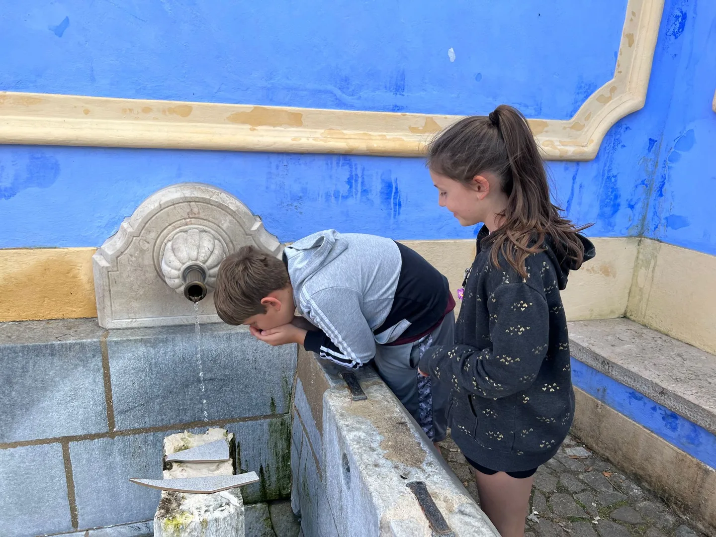 Children drinking from a tiled fountain