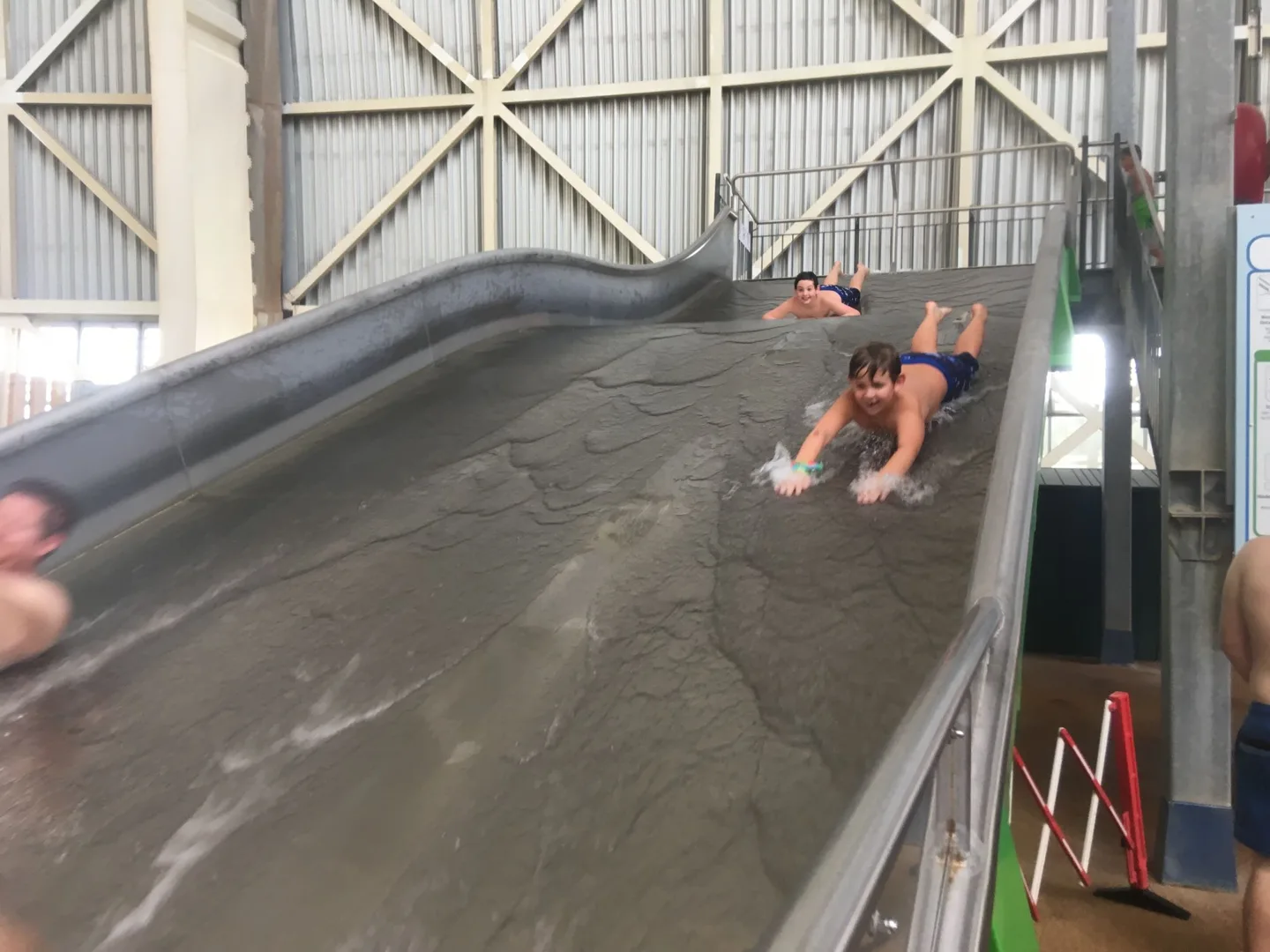 Child riding down a broad indoor slide