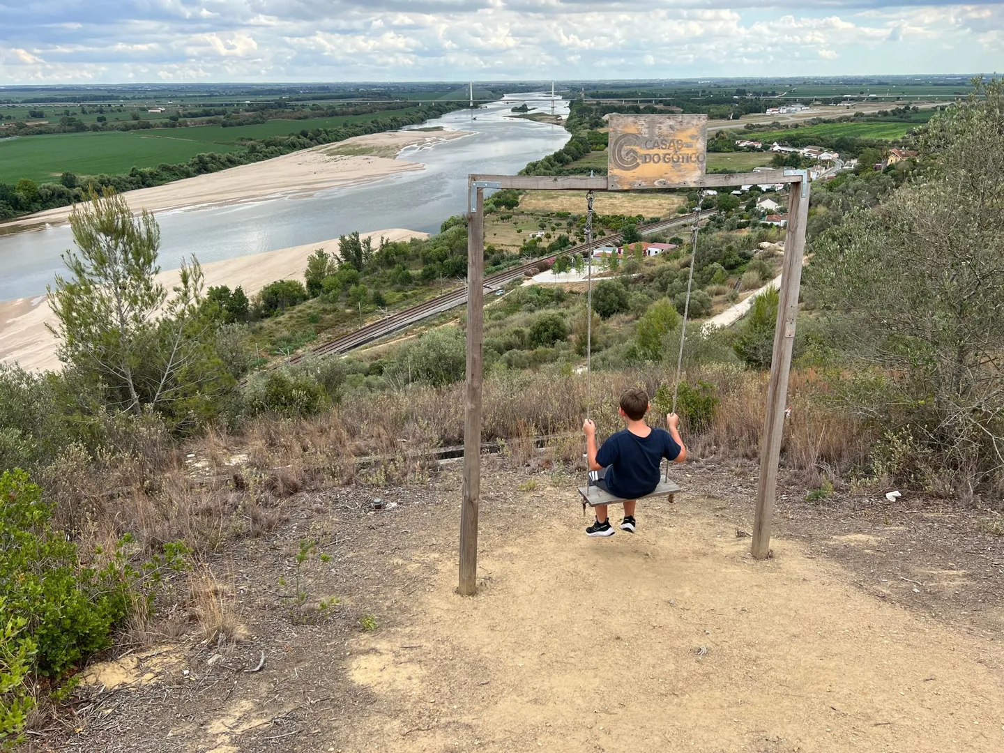 Child on a hillside swing overlooking the river