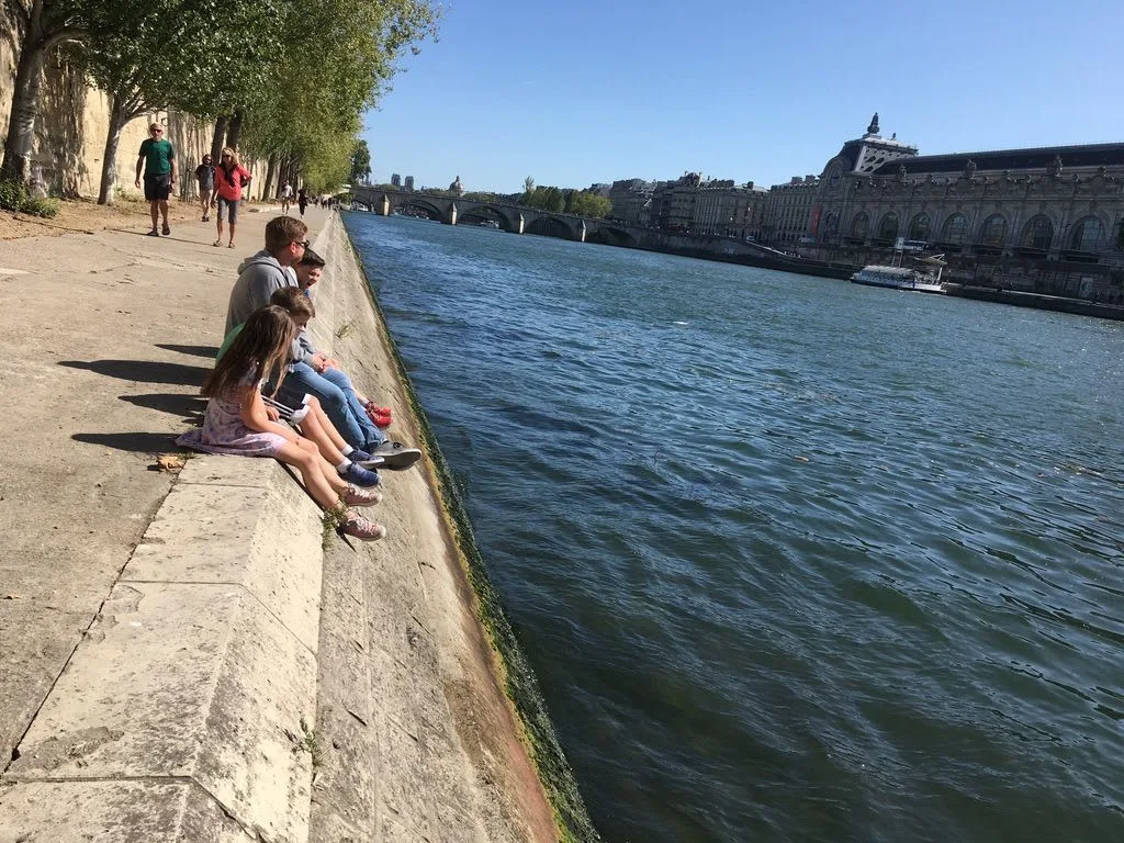 Children sitting on a wall beside the Seine