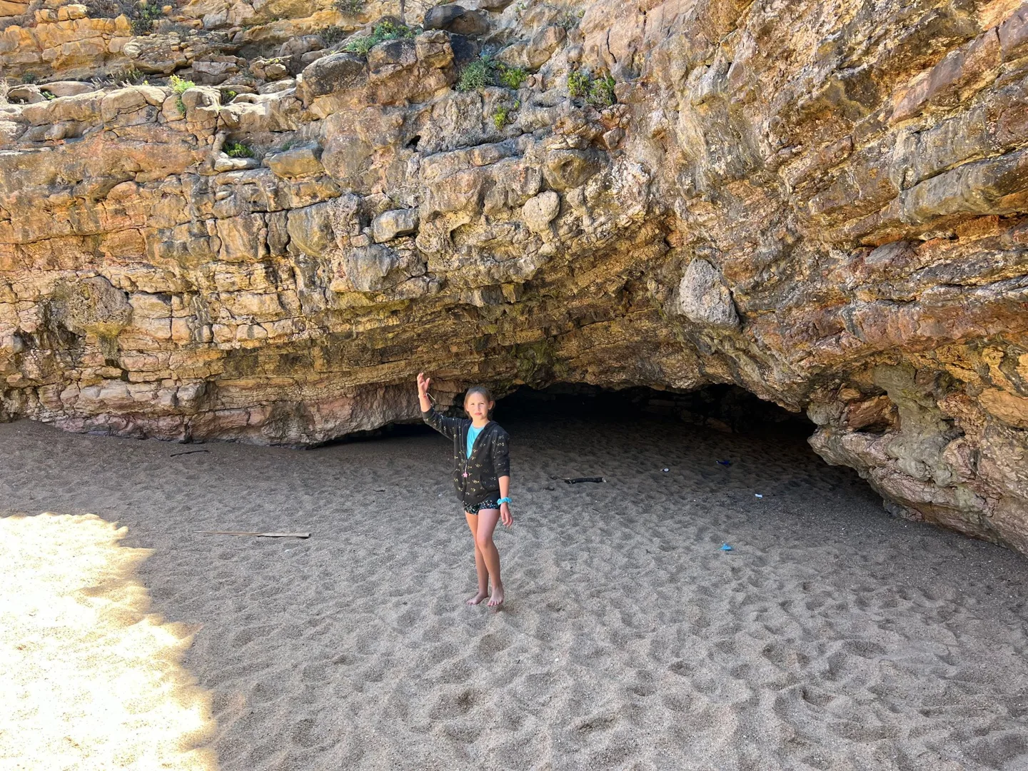 Child beneath an overhanging rock on the beach