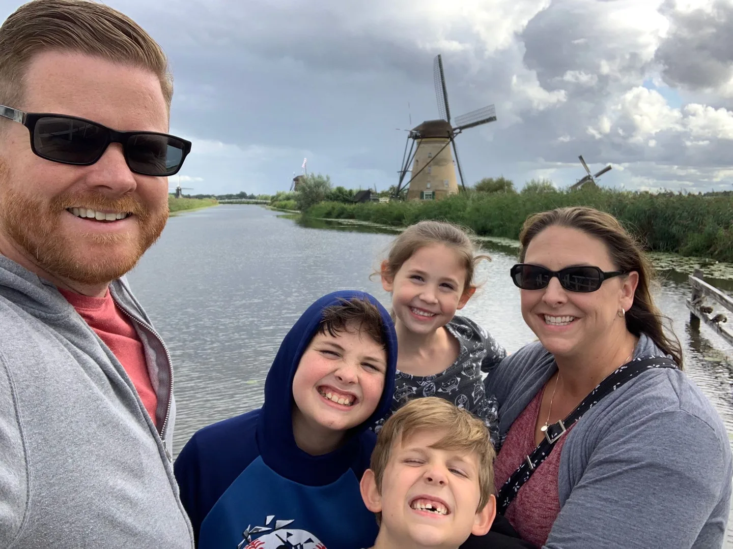 Family beside the water with a windmill behind them