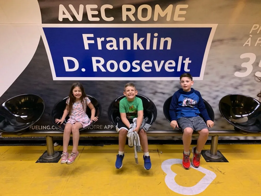 Children seated beneath a Franklin D. Roosevelt station sign