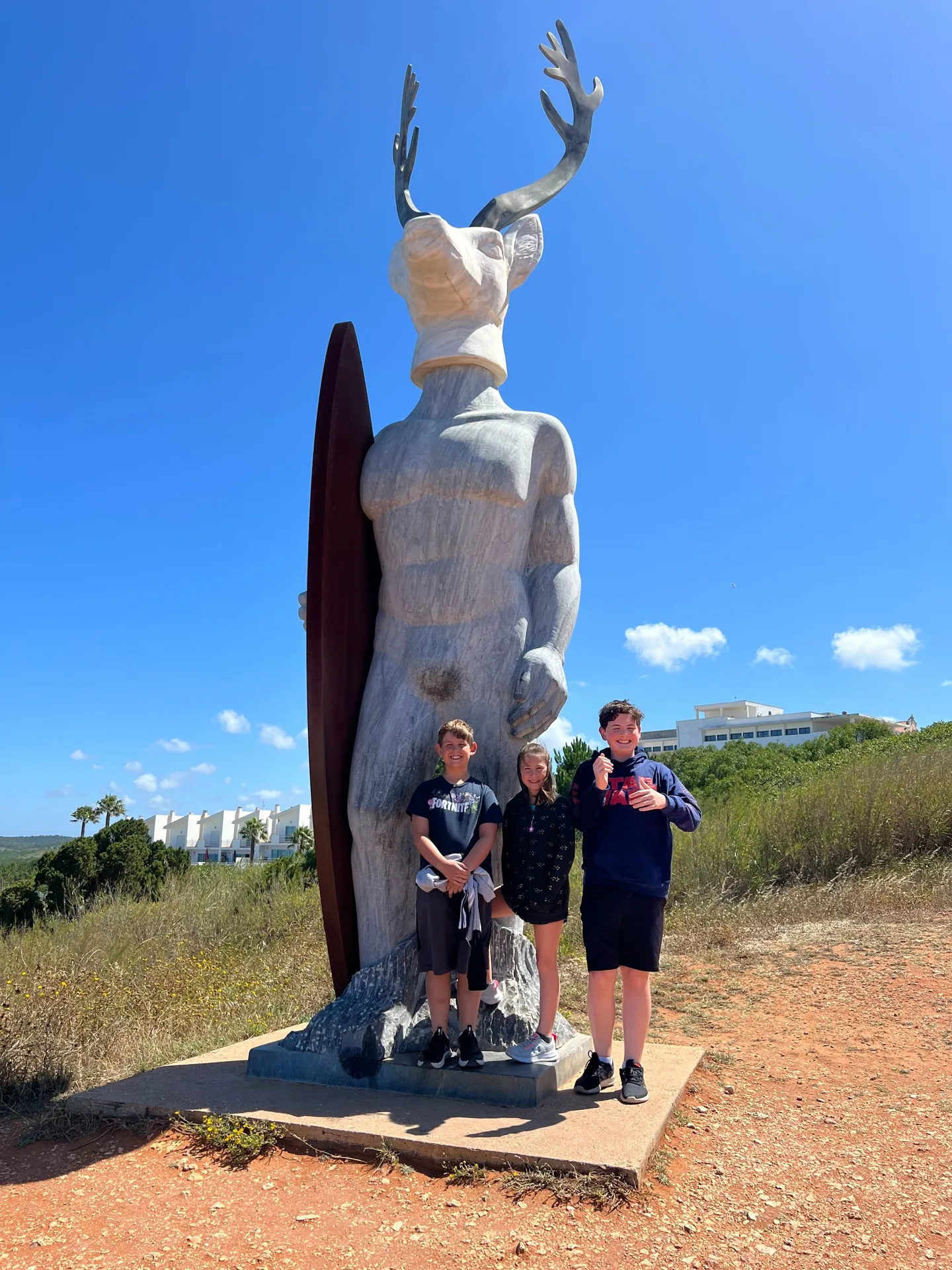 Children beside the deer-headed statue at Nazaré