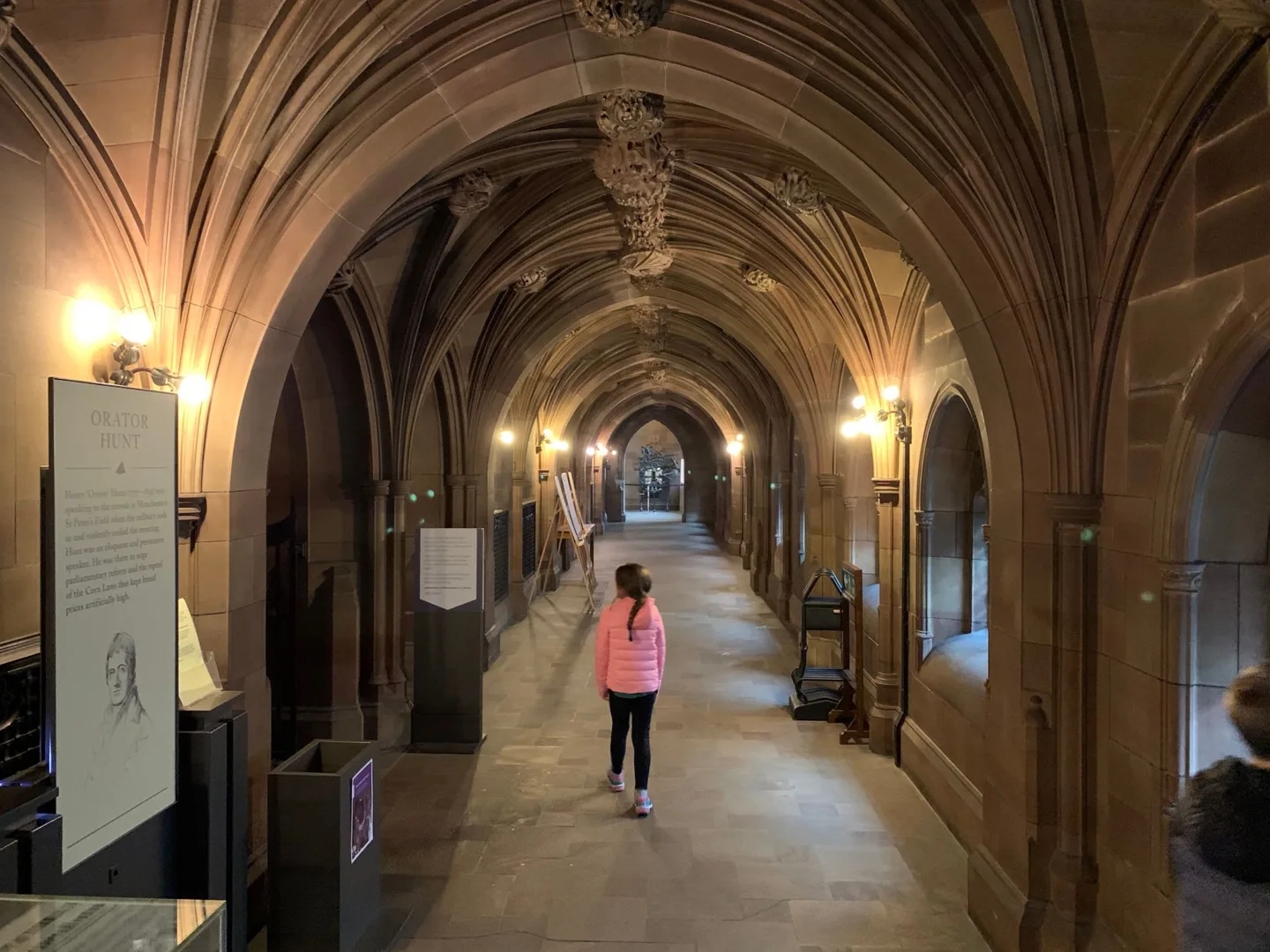 Child walking through an arched library corridor