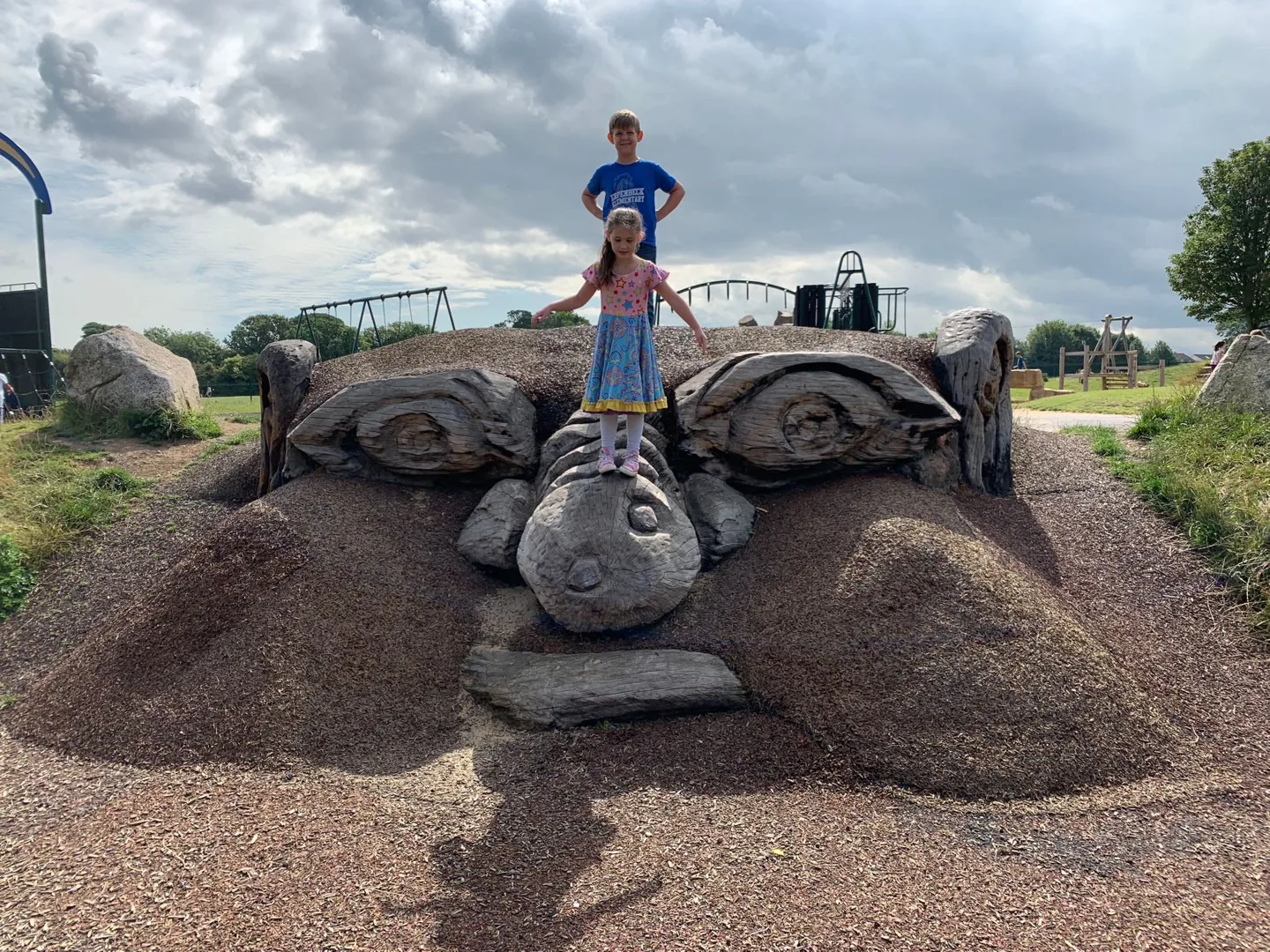 Child standing on a large playground sculpture