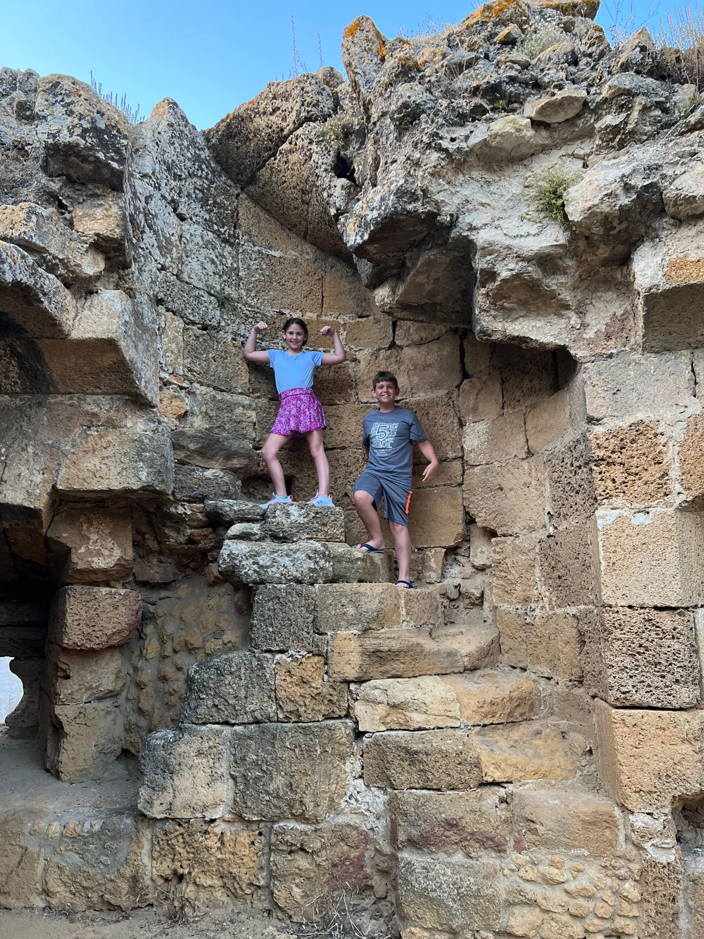 Children climbing through an opening in stone ruins