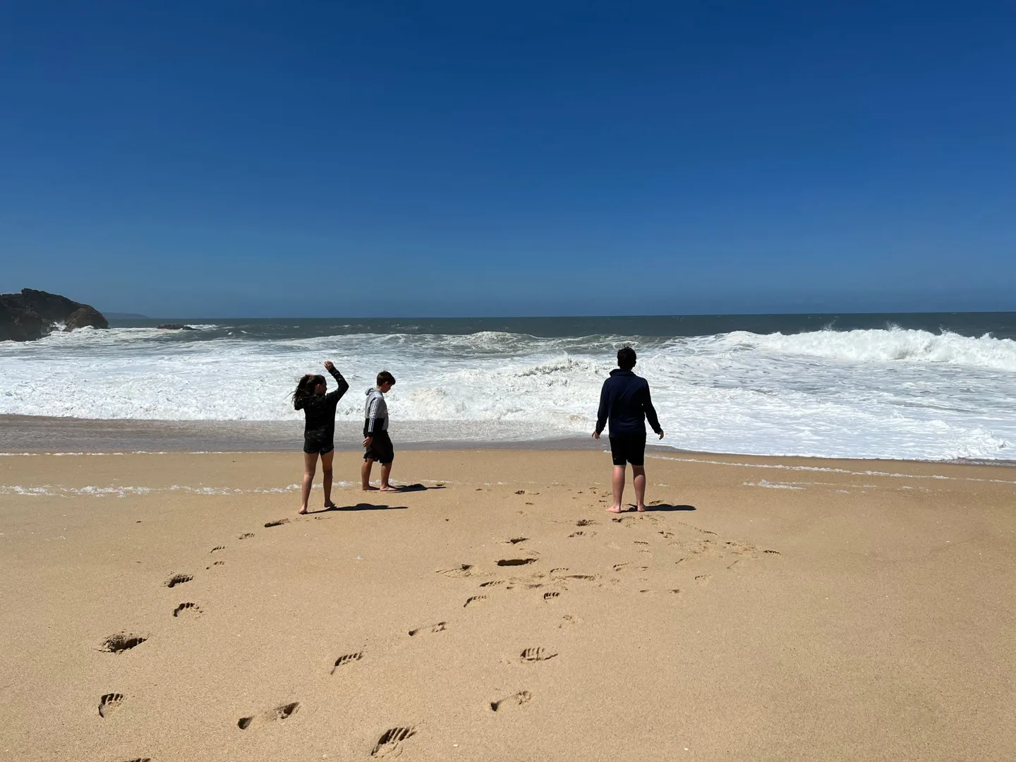 Children standing on the sand near the surf