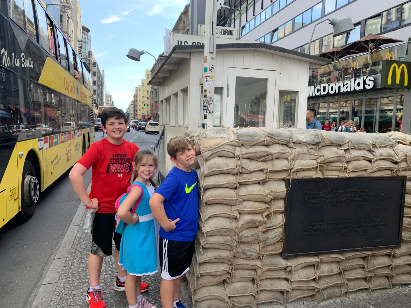 Children beside a checkpoint booth and sandbags