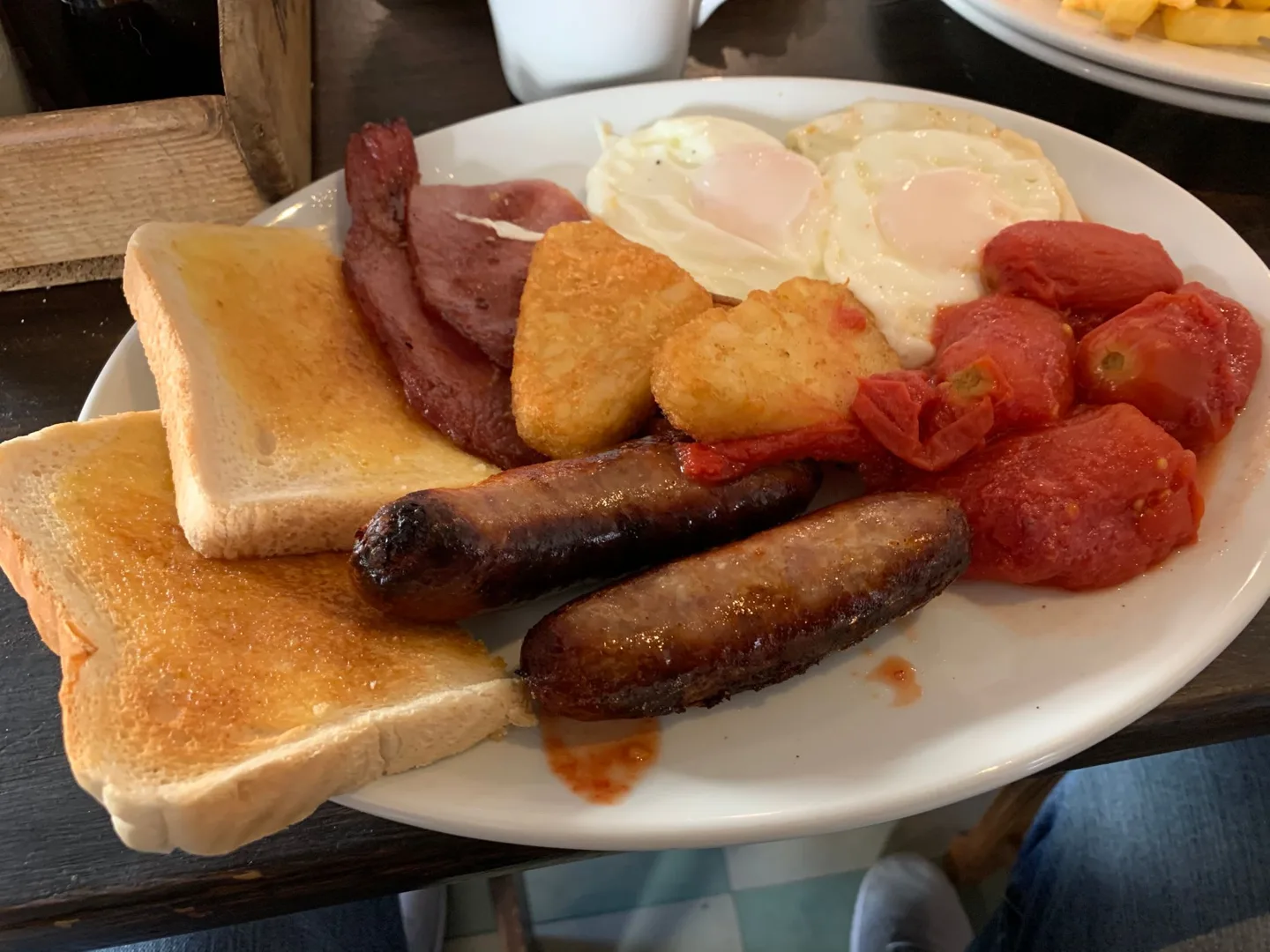 Full English breakfast with toast, eggs, sausage, and tomatoes