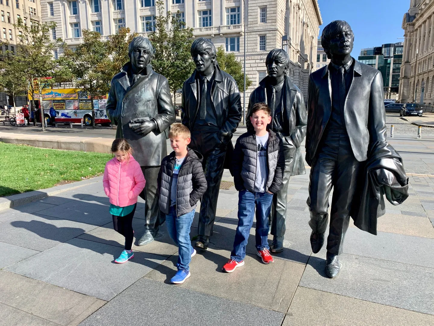 Children posing with the Beatles statues in Liverpool