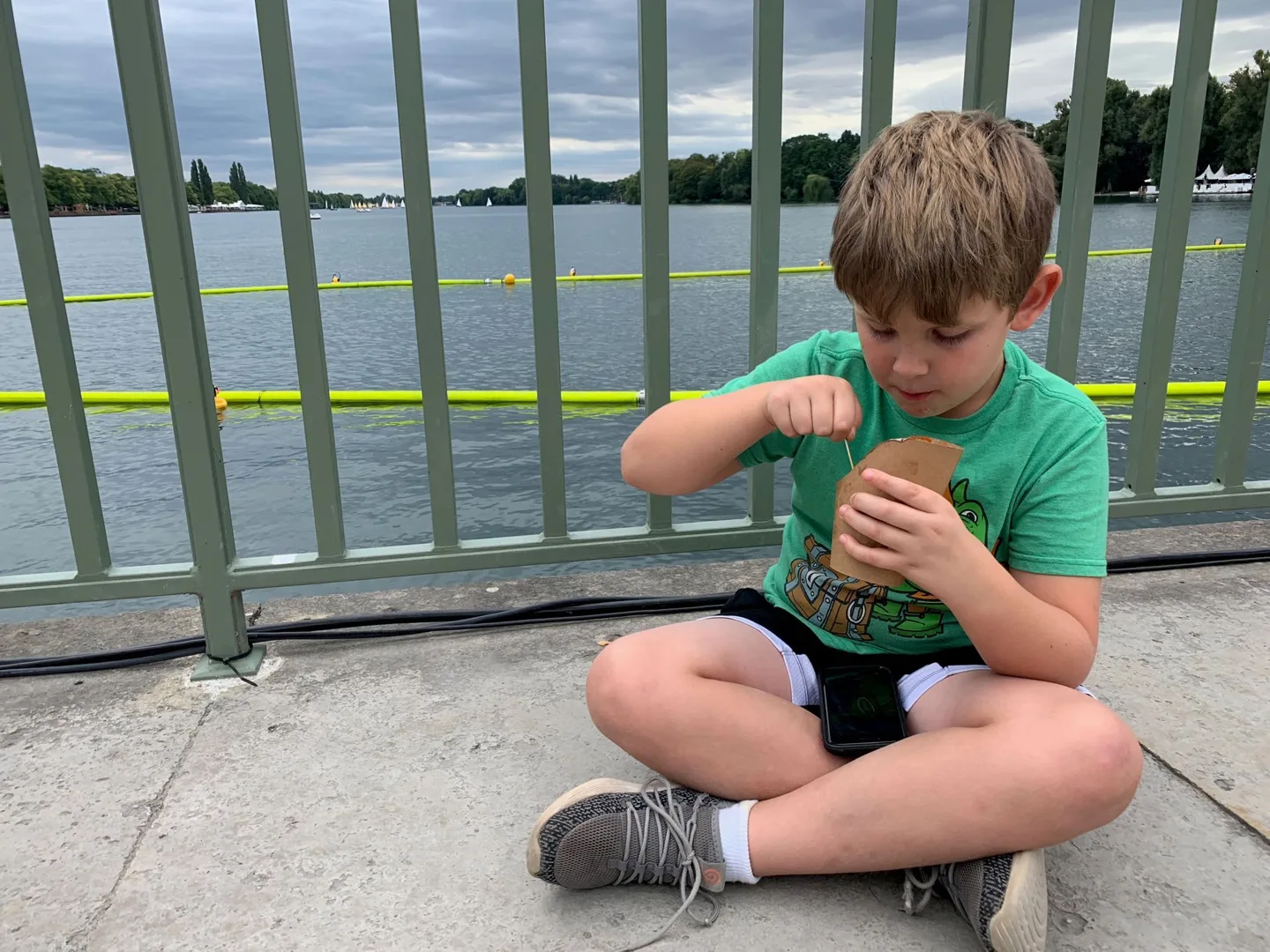 Child sitting by a railing with a snack