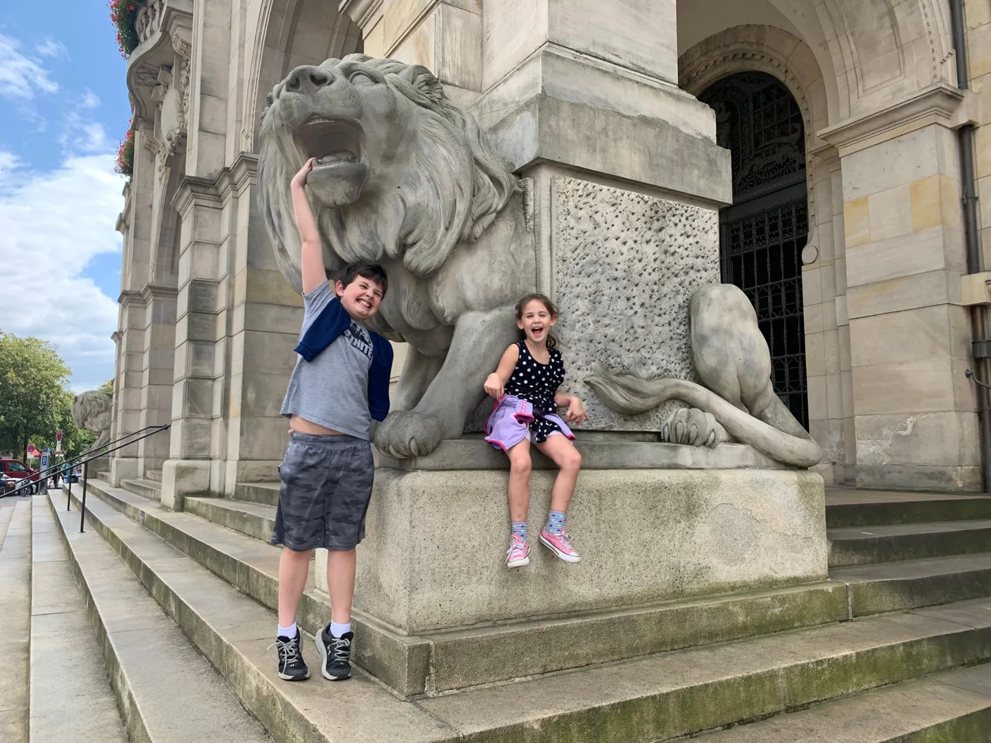 Children beside a stone lion at Hannover's New Town Hall