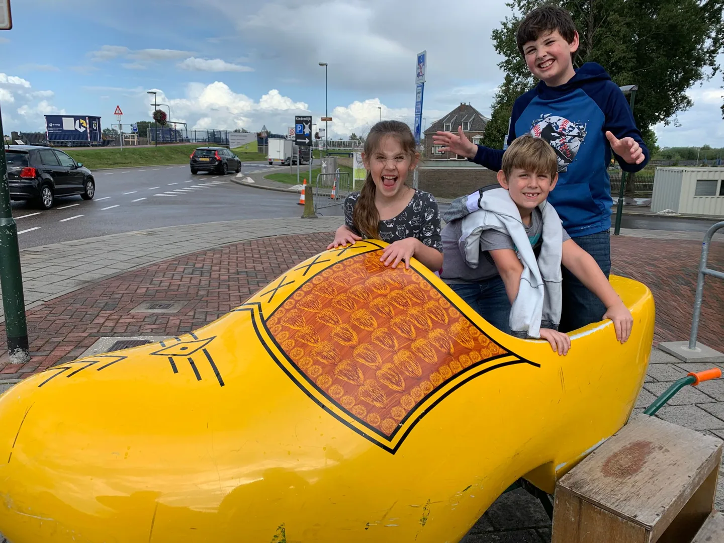 Children sitting inside a giant yellow wooden shoe