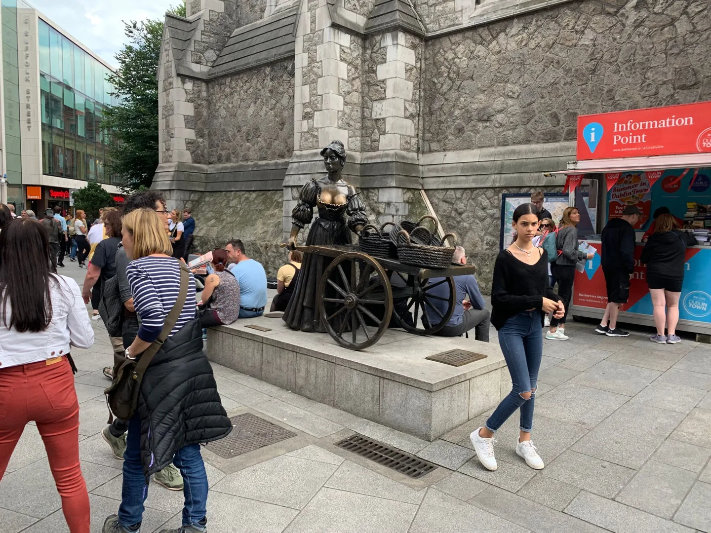 Street performer and audience beside a stone building